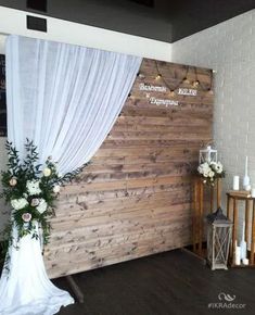 a wooden wall with white drapes and flowers on it