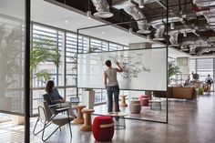 two people are writing on a whiteboard in an open room with chairs and tables