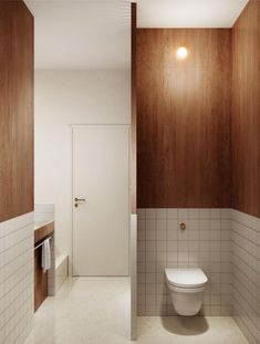 a white toilet sitting inside of a bathroom next to a wooden paneled wall and floor