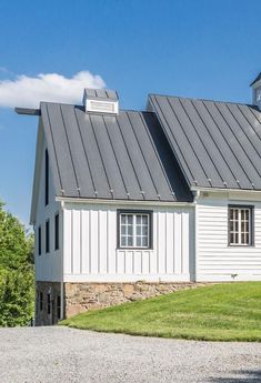 a white house with a black roof and two dormers on the top of it