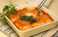 a casserole dish with spinach and cheese in it, on a table