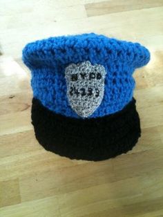 a crocheted hat with a police badge on it sitting on a wooden floor