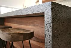 two wooden stools sitting next to a counter in a room with wood flooring