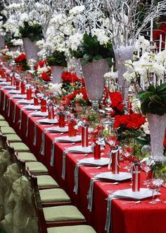 a long table with red cloths and white flowers in vases on each side