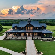 an aerial view of a large house in the middle of a green field at sunset