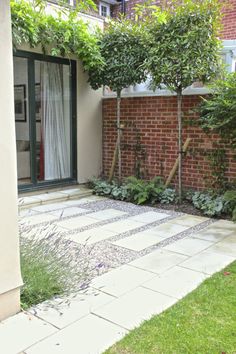 an outdoor patio with brick walls and green plants on the ground, surrounded by greenery