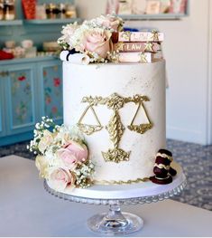 a white cake with gold scales and flowers on top, sitting on a table in front of a blue cabinet