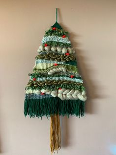 a knitted christmas tree hanging on the wall with balls and needles attached to it