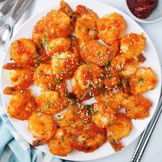 a white plate topped with fried shrimp next to a bowl of ketchup and dipping sauce