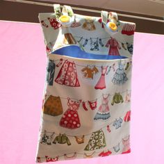 a bag hanging from a clothes line with clothes on it's side and buttons in the back