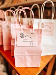 pink paper bags are lined up on a table with tags attached to the handles and sides