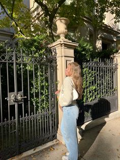 a woman is standing in front of a gate