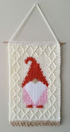 a crocheted wall hanging with a red and white gnome on it