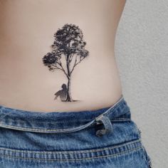 a woman's stomach with a small tattoo of a tree and a man sitting under it