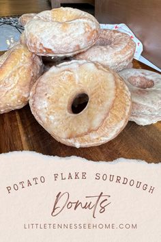 a pile of doughnuts sitting on top of a wooden table next to a sign that says potato flake sourdough donuts