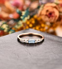 a diamond and gold ring sitting on top of a black box with flowers in the background