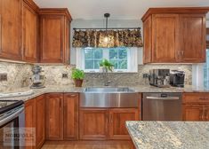 a kitchen with wooden cabinets and granite counter tops, stainless steel dishwasher on the center island