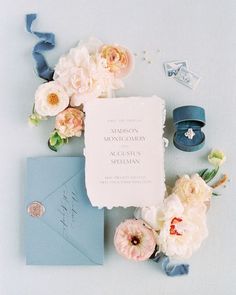 wedding stationery with flowers and rings on blue background