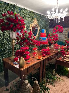 a table topped with lots of red flowers next to a wall covered in greenery