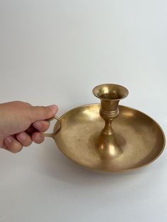 a person is holding onto a brass plate with a candle holder on the top and bottom