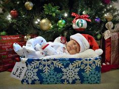 a baby is laying in a gift box under the christmas tree