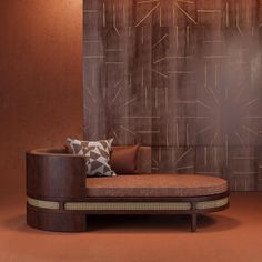 a round couch with pillows on it in front of a brown wall and wooden paneling