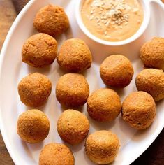 some food is on a white plate next to a small bowl with dipping sauce in it