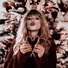 a woman holding a heart shaped lollipop in front of a christmas tree