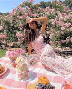 a woman sitting at a picnic table in front of pink flowers with her hands on her head