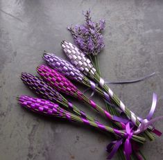 purple and white flowers are laid out on the ground next to each other with ribbons tied around them