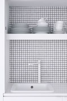 a white kitchen sink sitting under a shelf filled with dishes