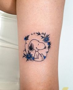 a woman's leg with a small tattoo of a dog and flowers on it