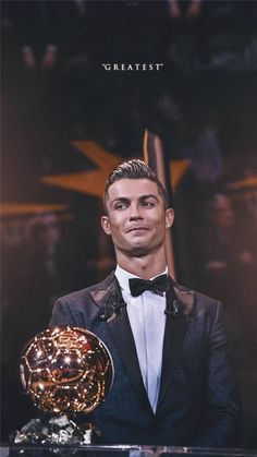 a man in a tuxedo holding a golden soccer ball and posing for the camera