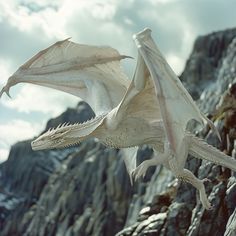 a white dragon flying over a rocky mountain