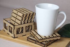 a cup and coasters sitting on top of a wooden tray next to a leaf