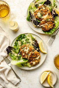 two plates with chicken patties, lettuce and lemon wedges