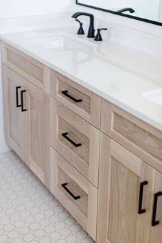 a bathroom vanity with two sinks and a large mirror over the counter top that has black handles on it