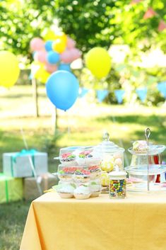 a table topped with lots of desserts and balloons