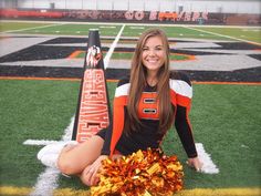 a cheerleader is sitting on the field with her pom - poms