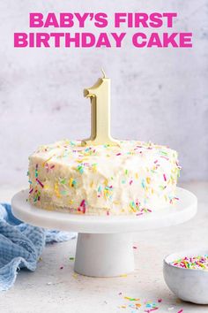 a first birthday cake with white frosting and sprinkles on the top