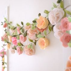 flowers are hanging on the wall next to each other with green leaves and pink roses