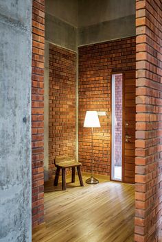 an empty room with brick walls and wooden flooring is seen through the doorway to another room