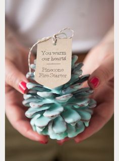 a person holding a small pine cone with a tag on it's end that says, you wear our heart