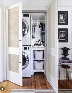 a washer and dryer in a small room next to a door with some clothes hanging on it