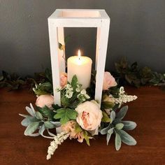 a white candle holder with flowers and greenery