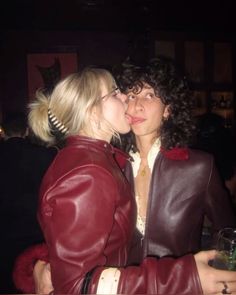 two women in leather jackets kissing each other