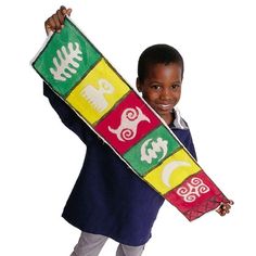 a young boy is holding up a colorful board with animals and letters on it while standing in front of a white background