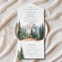 a wedding card with watercolor trees and mountains in the background on a white sheet