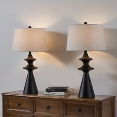 two lamps sitting on top of a wooden dresser