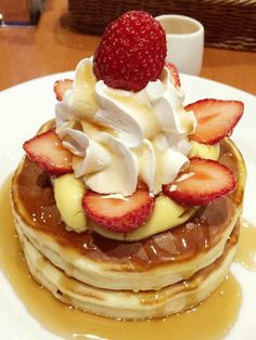 a stack of pancakes topped with whipped cream and strawberries